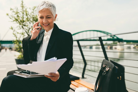 Middle-aged businesswoman sitting on a bench and talking on a cellphone