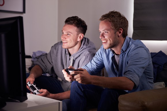 Two guys sitting on a couch playing video games. 
