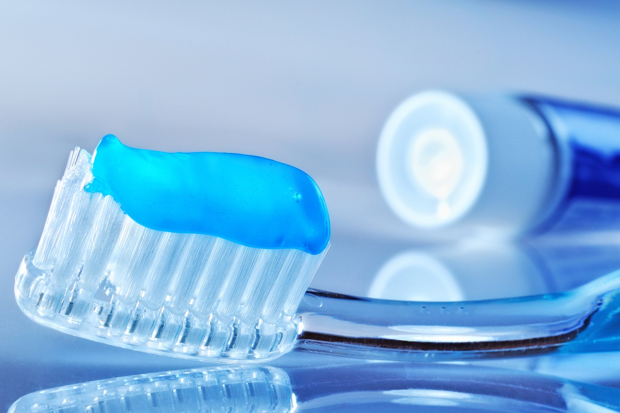 A close up of a toothbrush with blue toothpaste on it. 