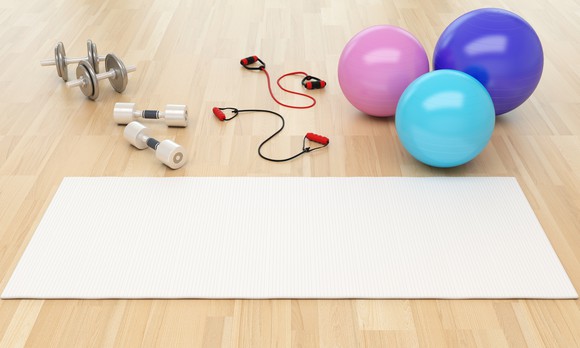 A grouping of exercise equipment in a gym, including a yoga mat and barbells