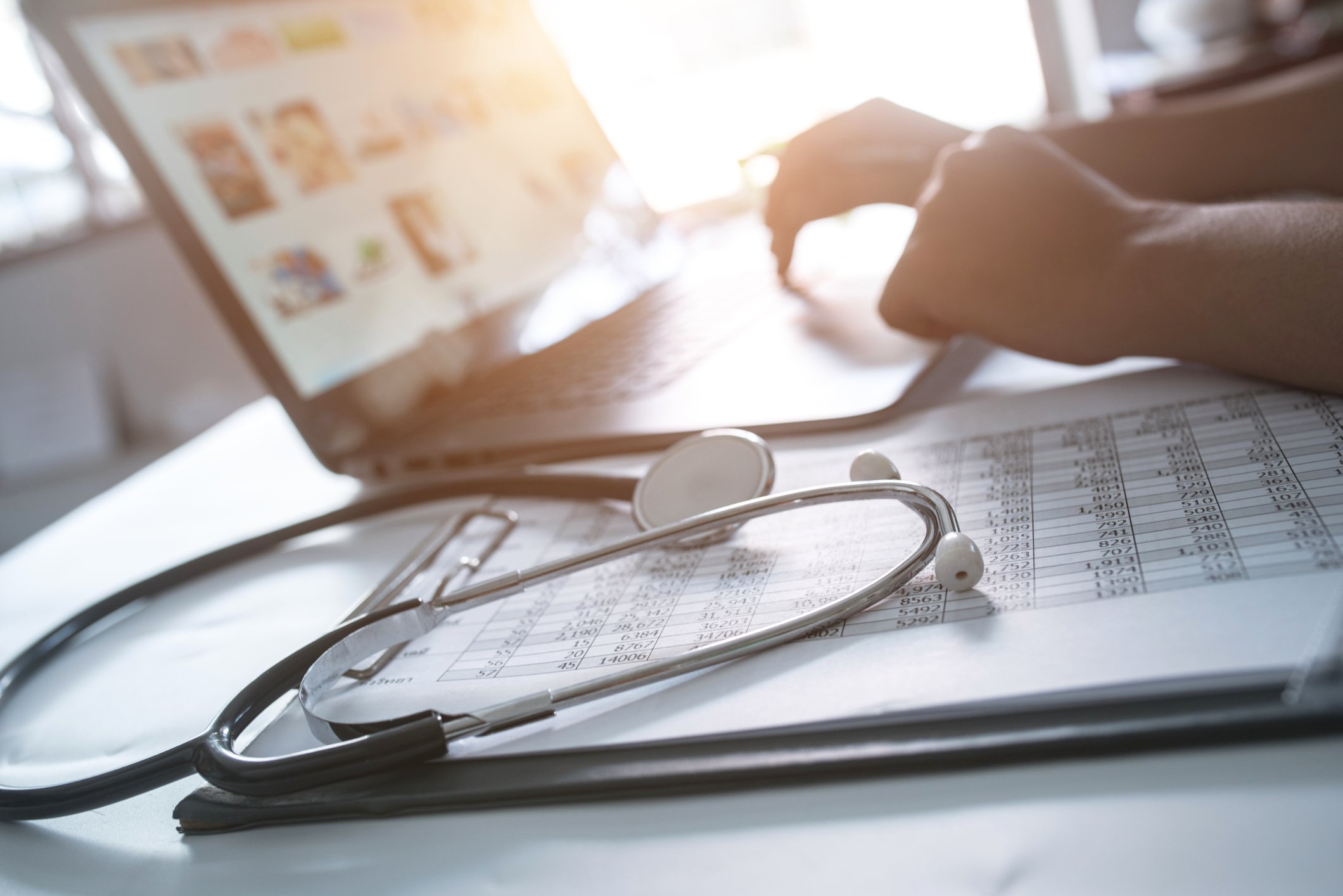 A doctor working on the computer with a stethoscope in the foreground.