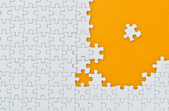 Photo of white puzzle pieces on orange background.