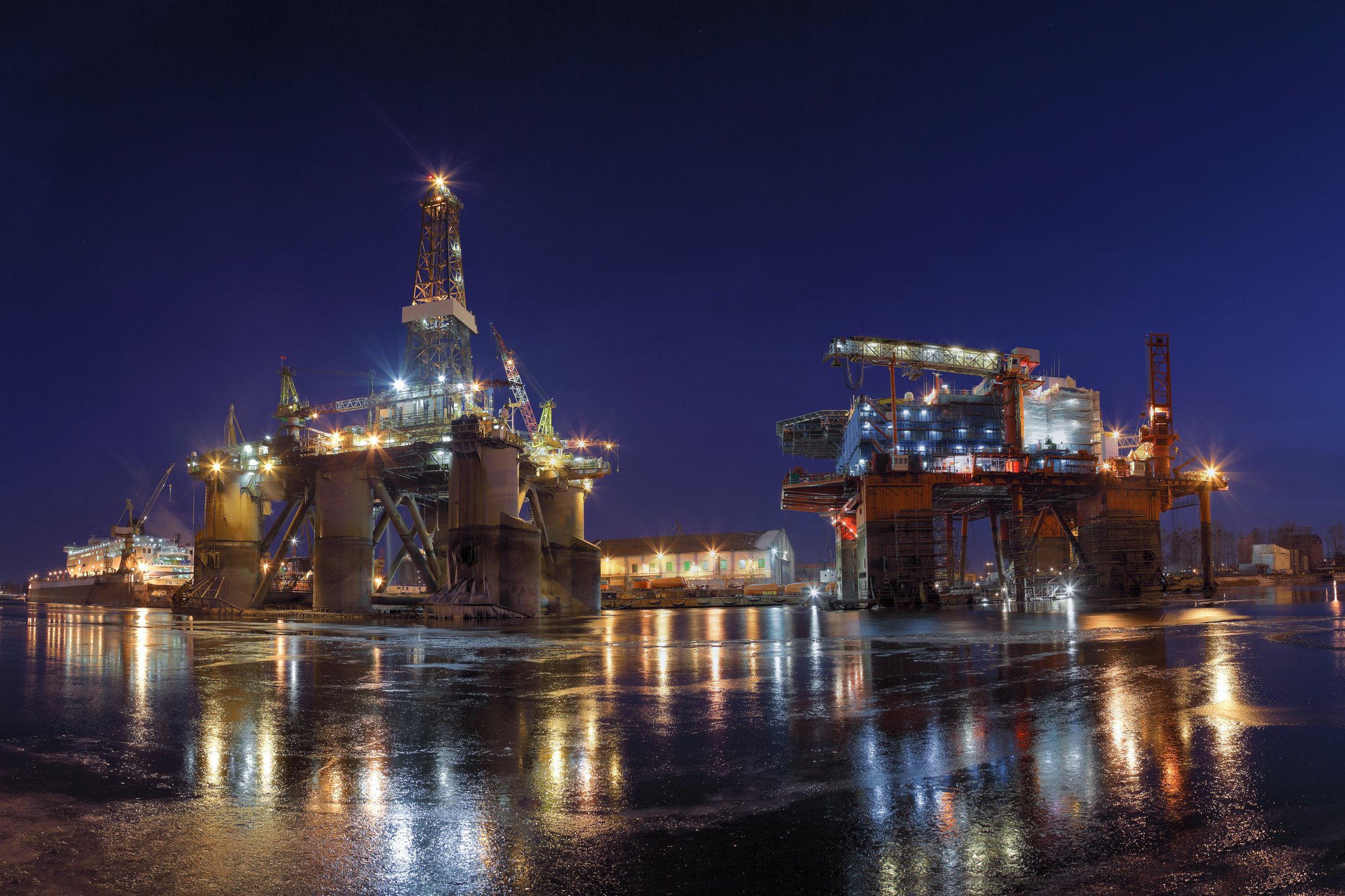 idle offshore rigs in a shipyard at night