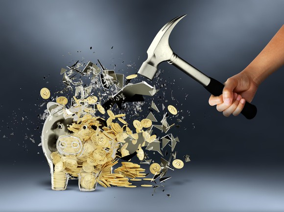 Person smashing piggy bank with hammer