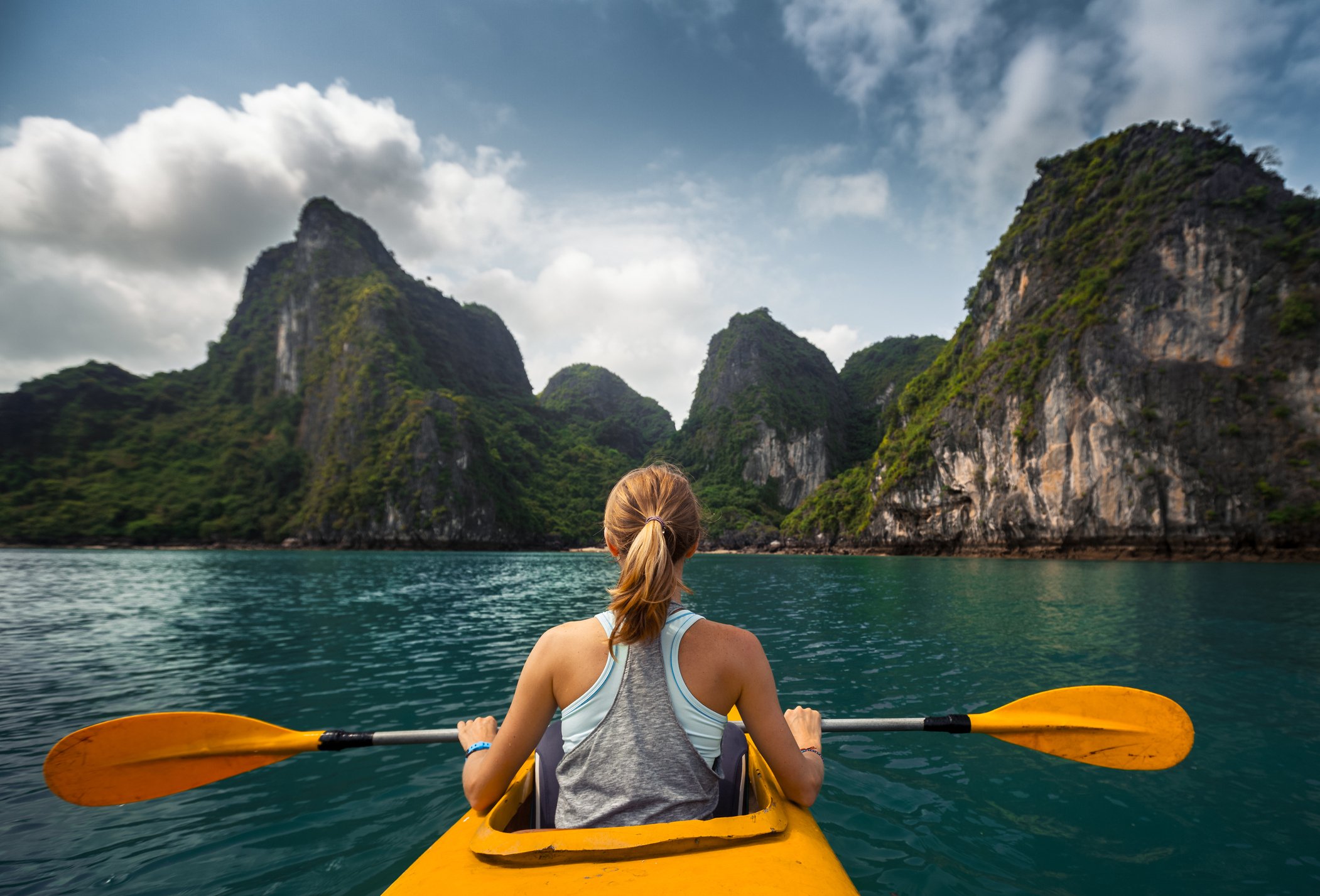 Woman in a yellow kayak overlooking a beautiful island.