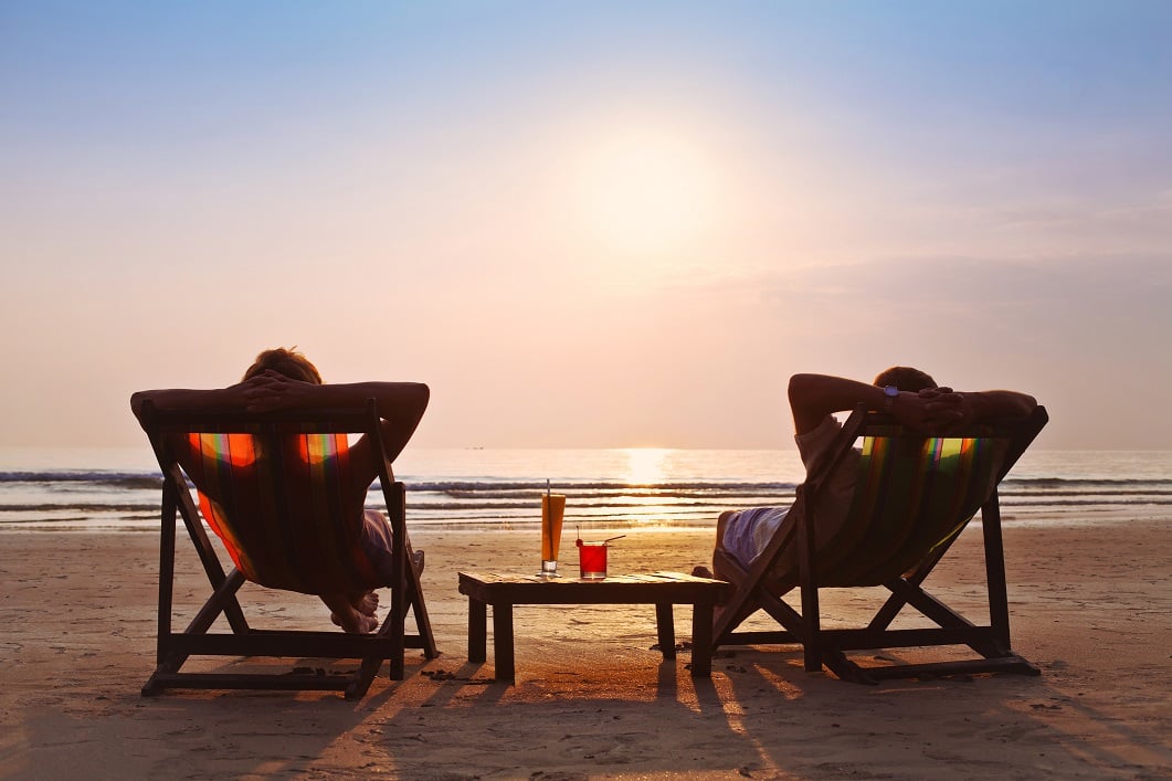 A couple rests on beach chairs to watch the sunset.