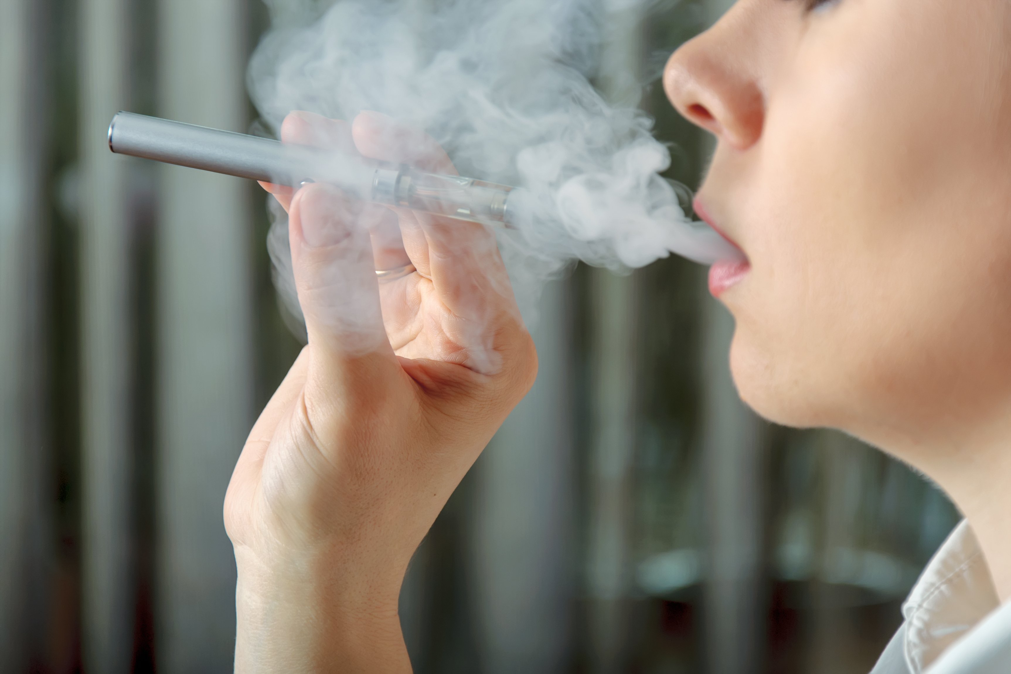 Woman using an electronic cigarette and exhaling a vapor
