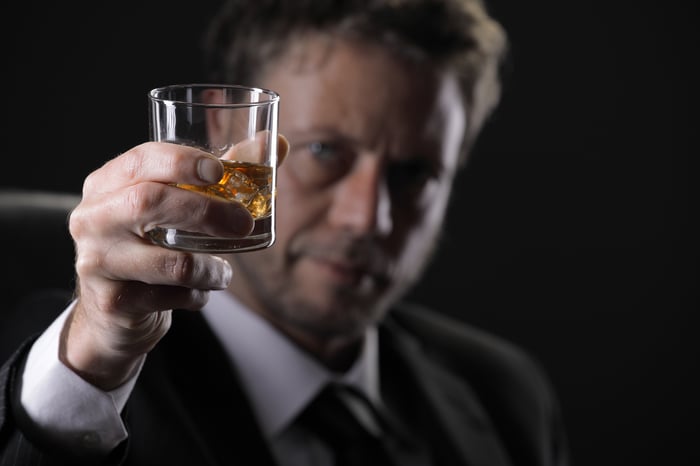 Well-dressed man raising a glass of whiskey in toast