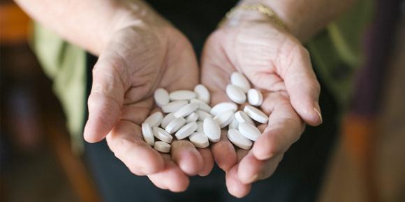 Outstretched hands holding a pile of tablets.
