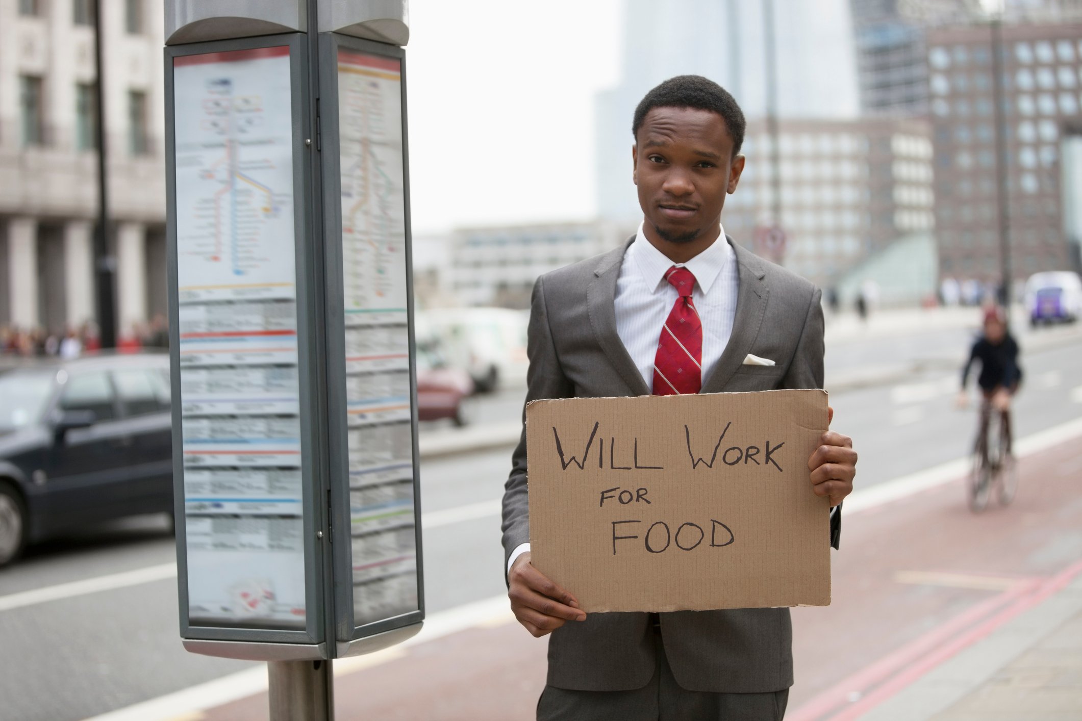 Broke businessman with Will Work for Food sign