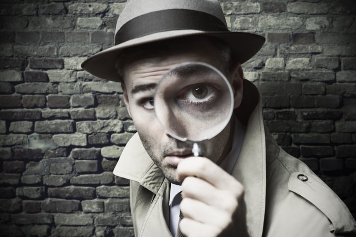 Detective looking through a magnifying glass.