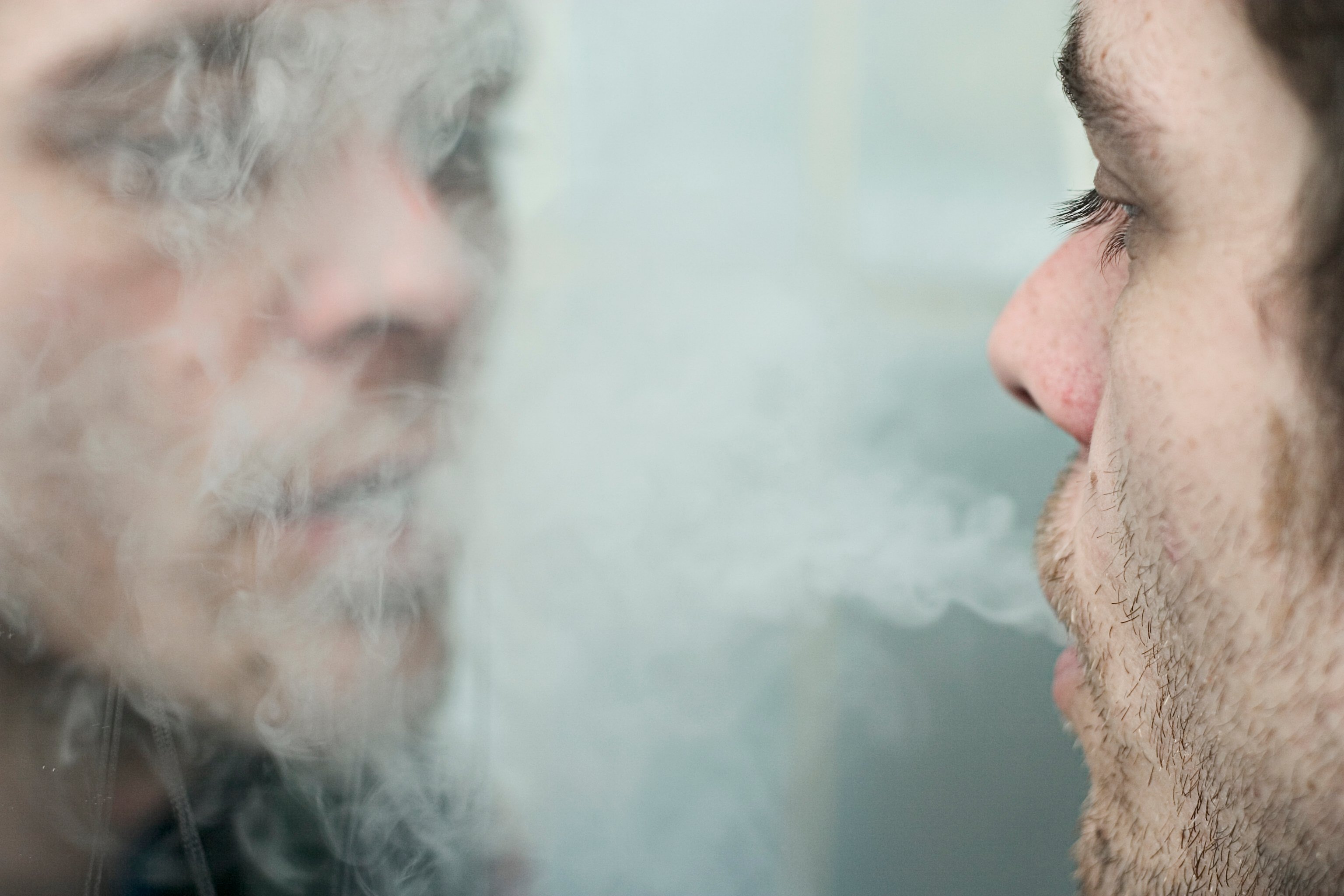 Man blowing smoke into a mirror. 