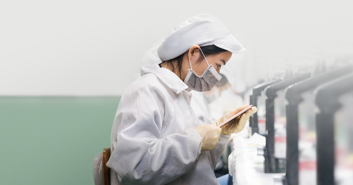 A worker assembles parts of an apple product. 