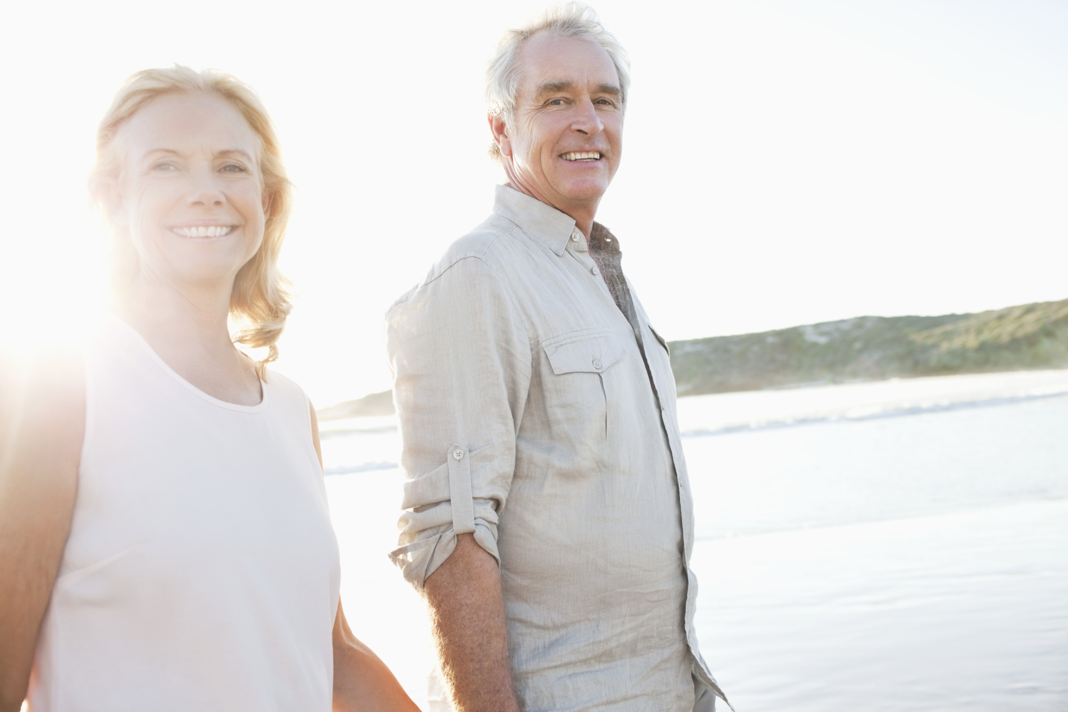 Retired couple walking on the beach.