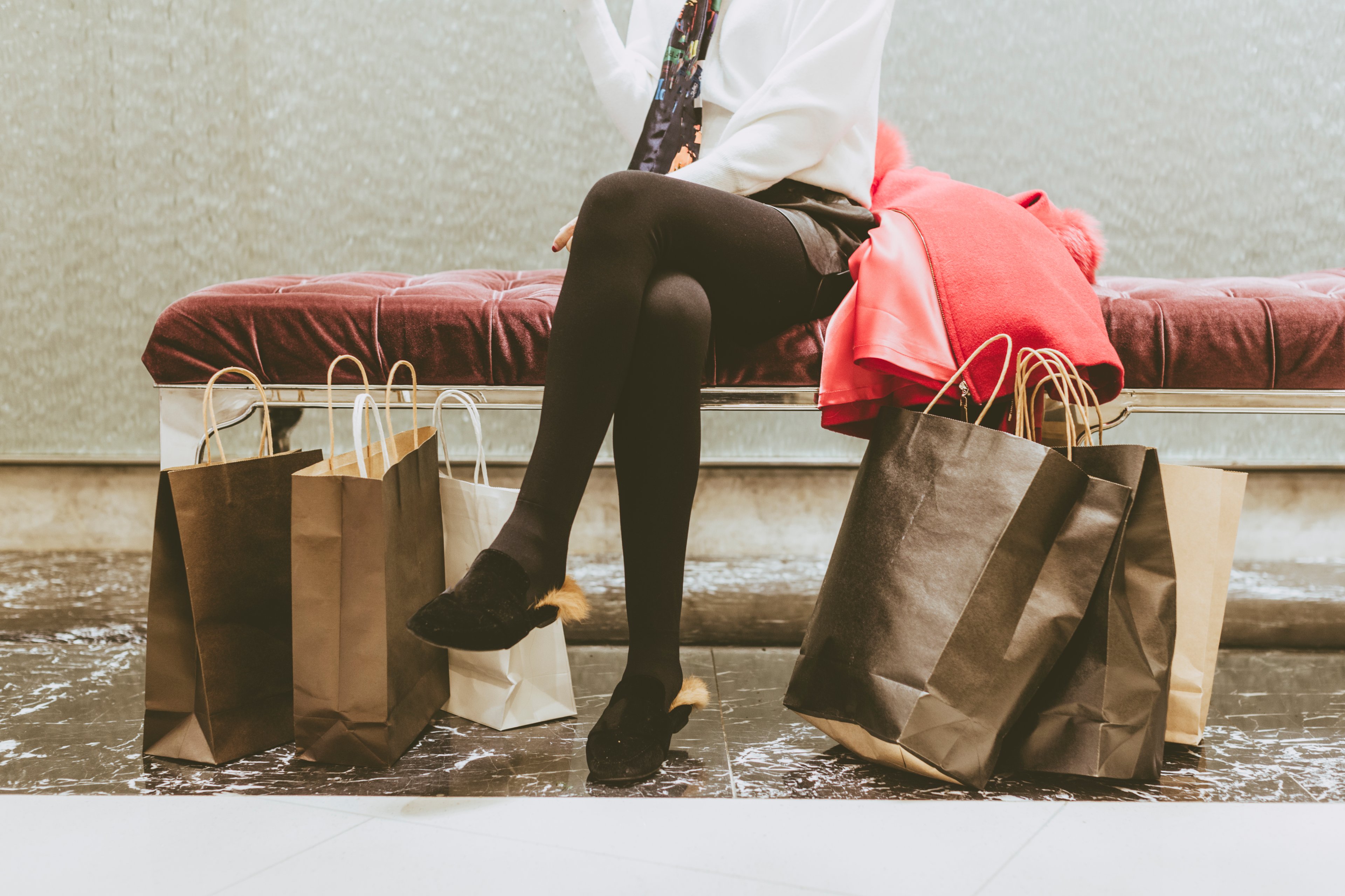 Woman sitting on bech with several shopping bags at her feet. 