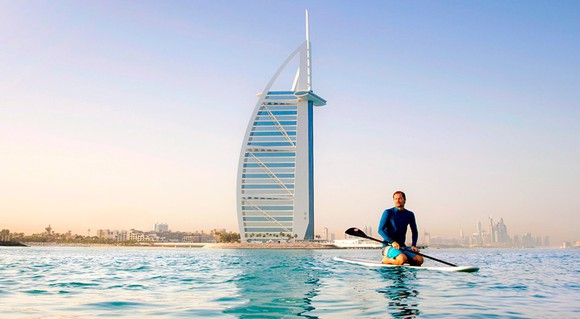 A man rides a paddle board on a lake in Dubai.
