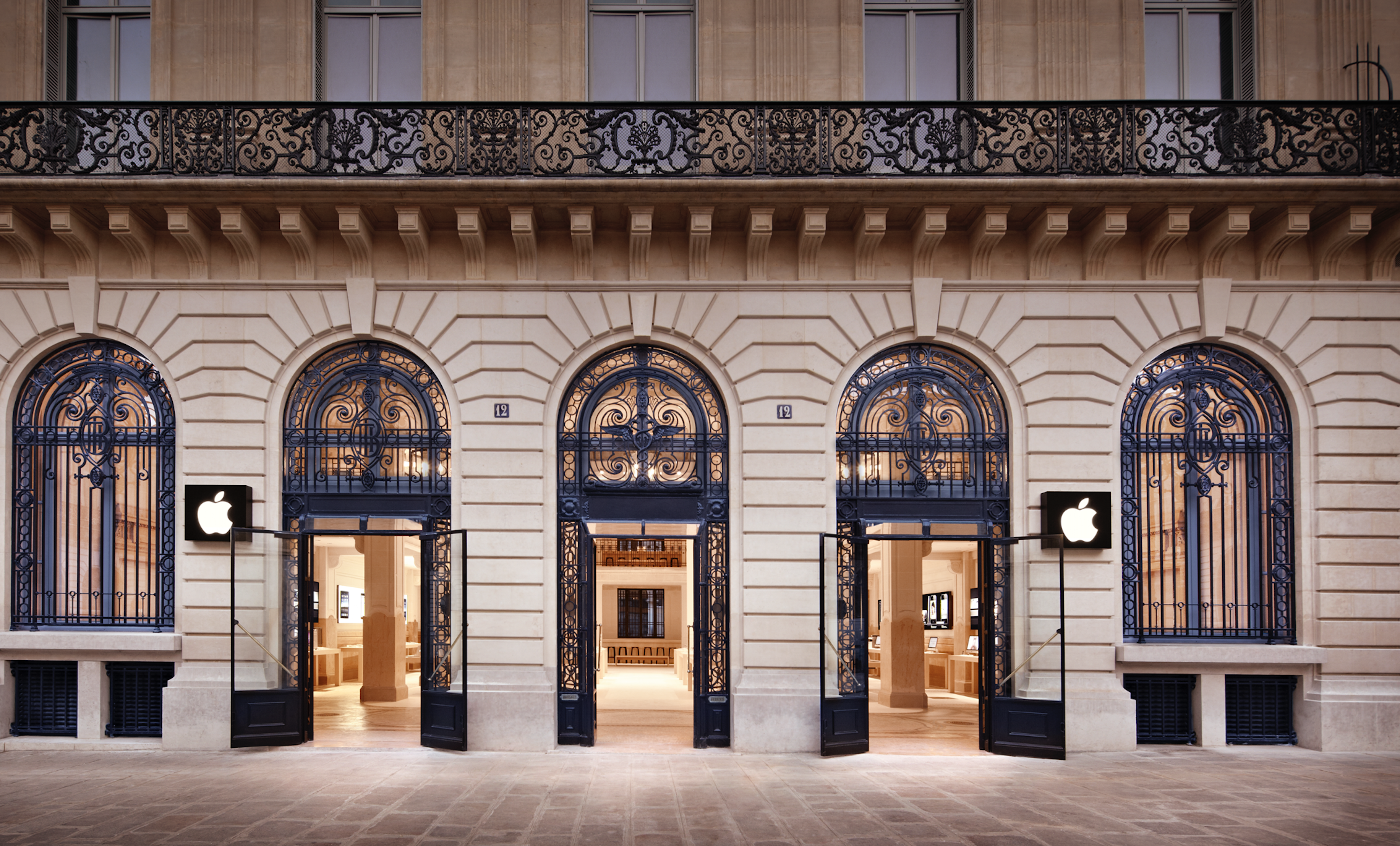 Apple storefront in Paris with black Apple logo in window display.