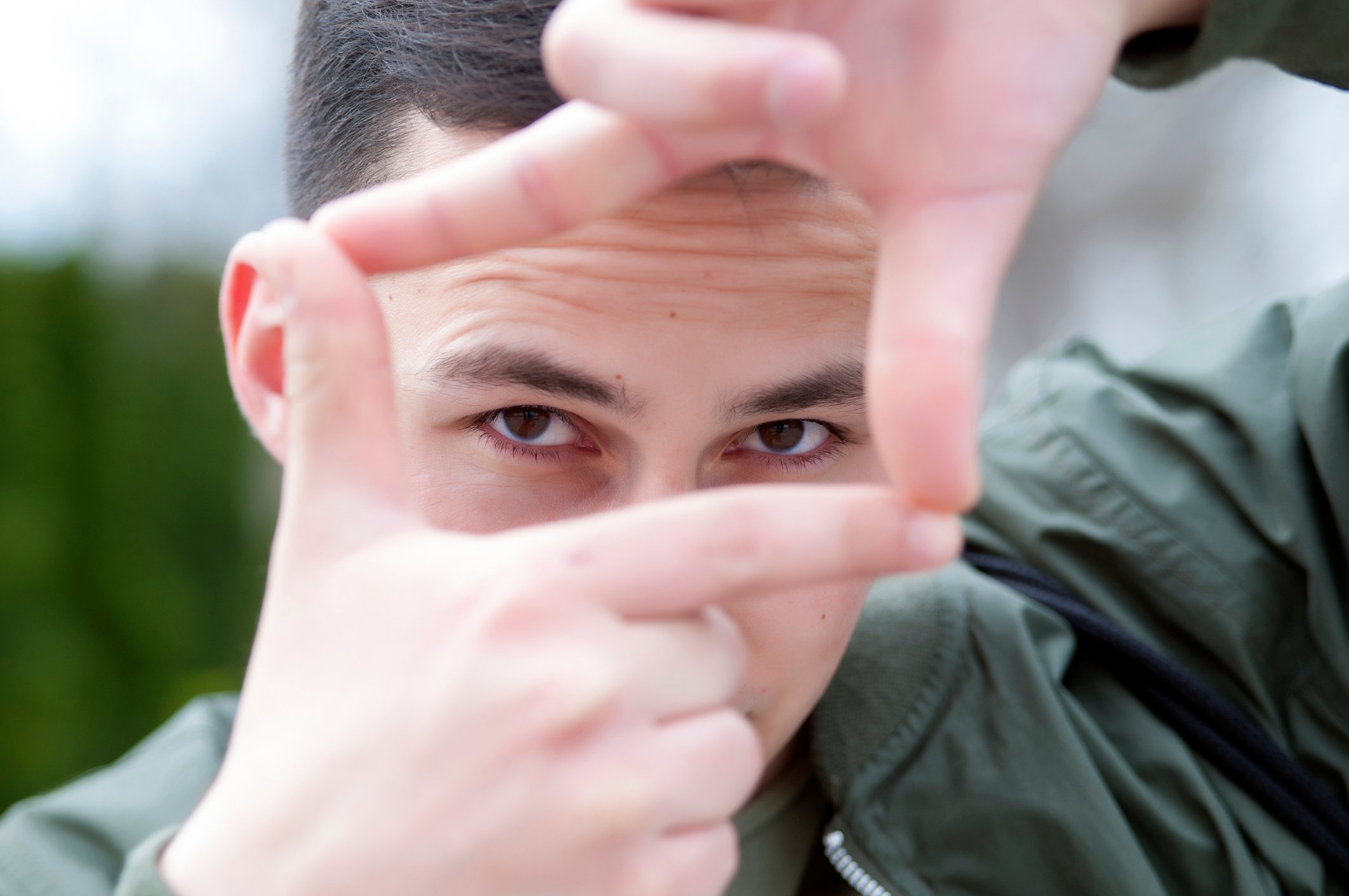 Young man looking through a square made with his fingers