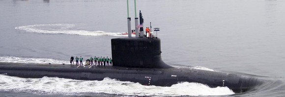 Nuclear submarine in the water, with a crew standing on deck.