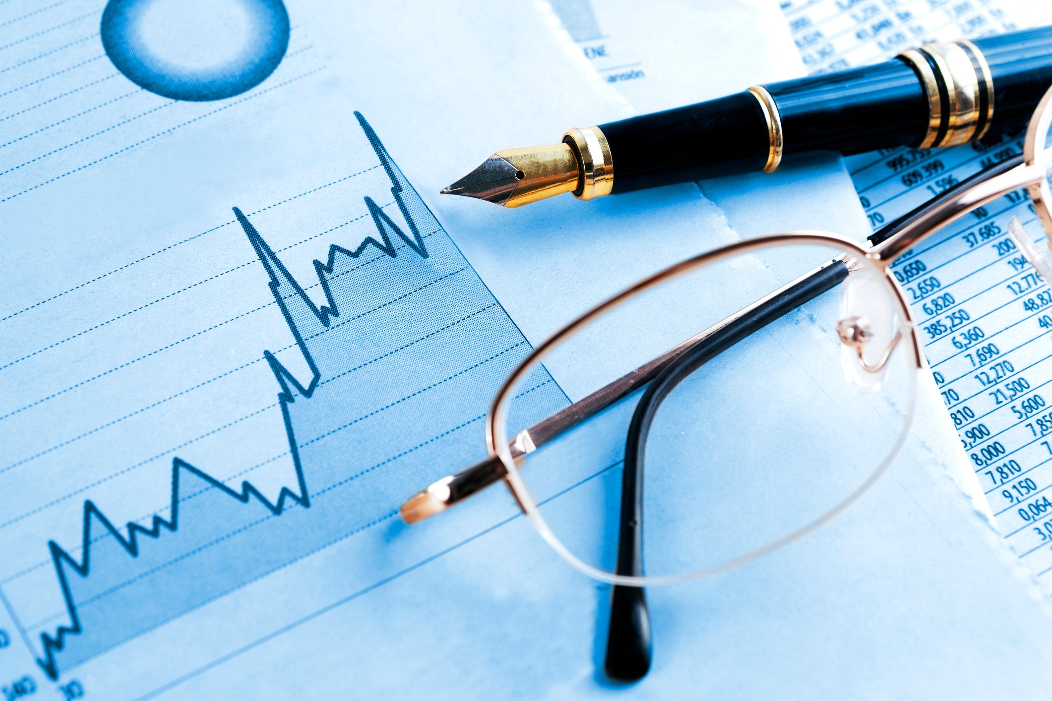 Rising stock chart, pen, and eyeglasses