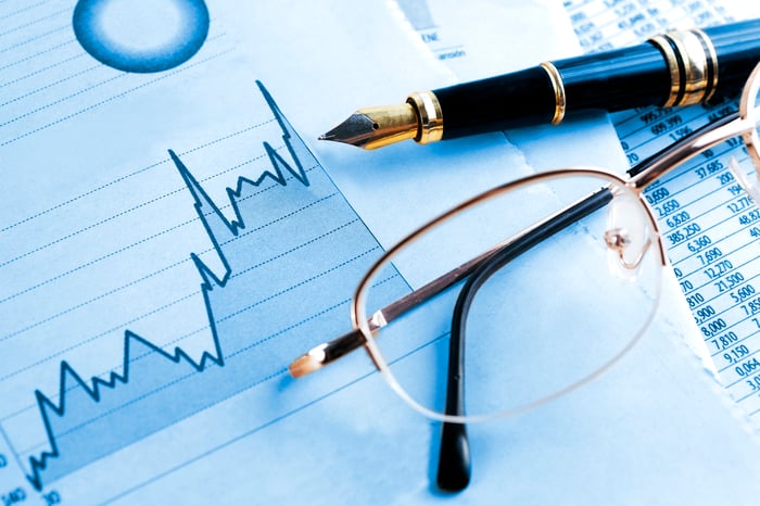 Rising stock chart, pen, and eyeglasses