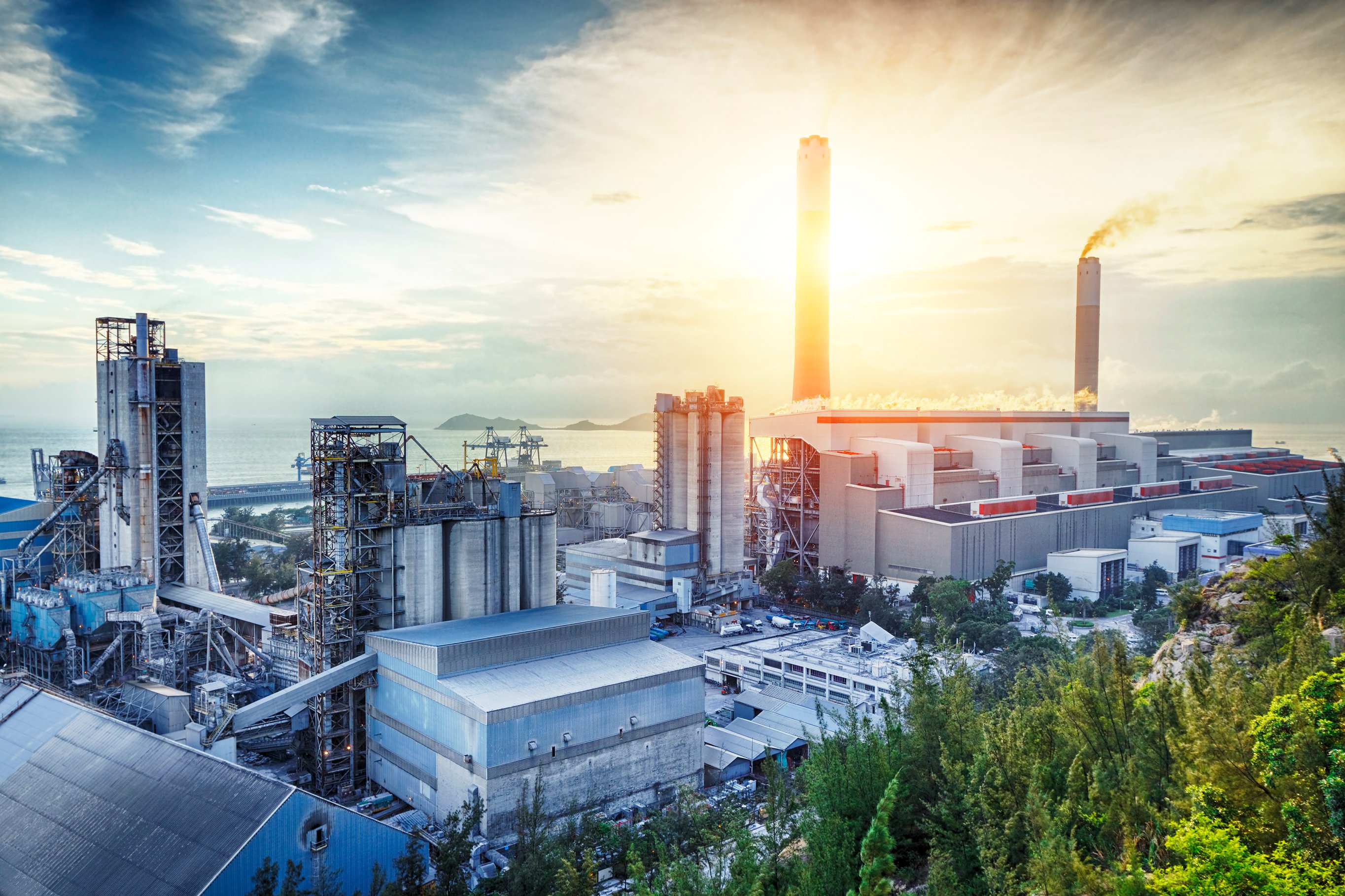 A power plant by the water shown at sunrise. 