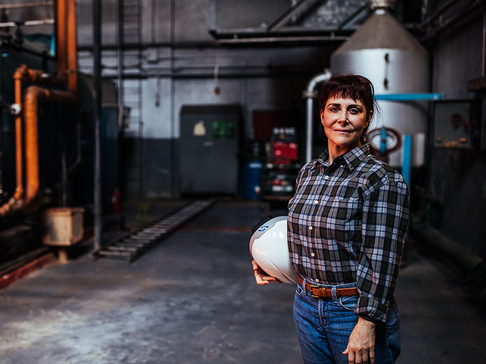A woman in an industrial setting holding a DAQRI Smart Helmet.