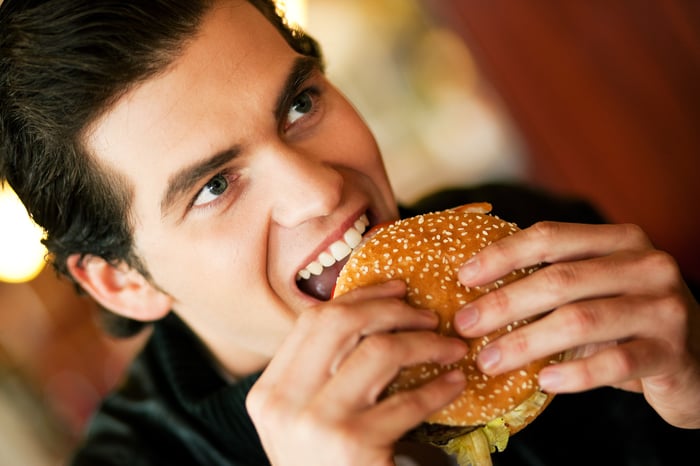 A man taking a bite out of a hamburger.