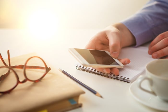Hand holding a phone at a desk
