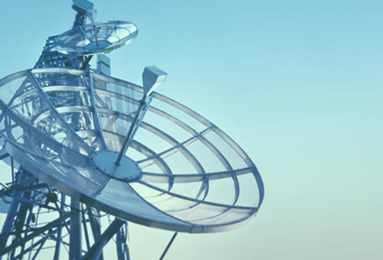 A satellite dish against a pale blue sky.