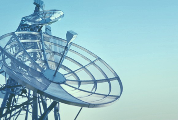 A satellite dish against a pale blue sky.