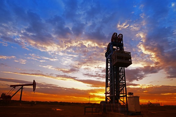 An oil rig and oil pump sunset.