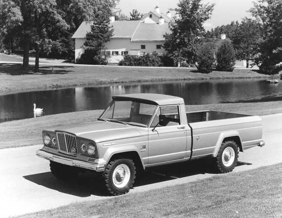A black and white photo of a 1968 Jeep Gladiator pickup truck in a farm setting.