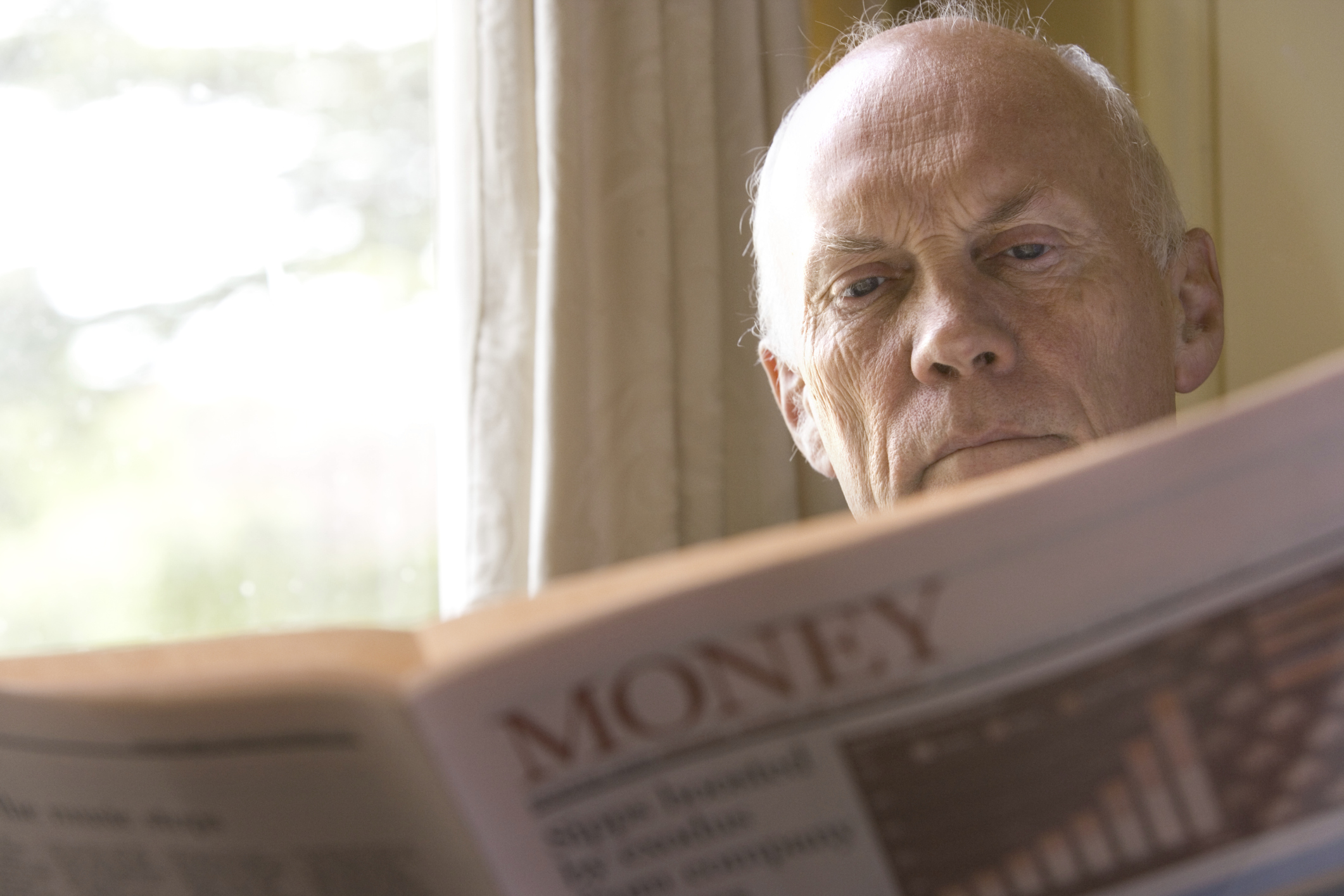 A senior man reading a financial newspaper. 