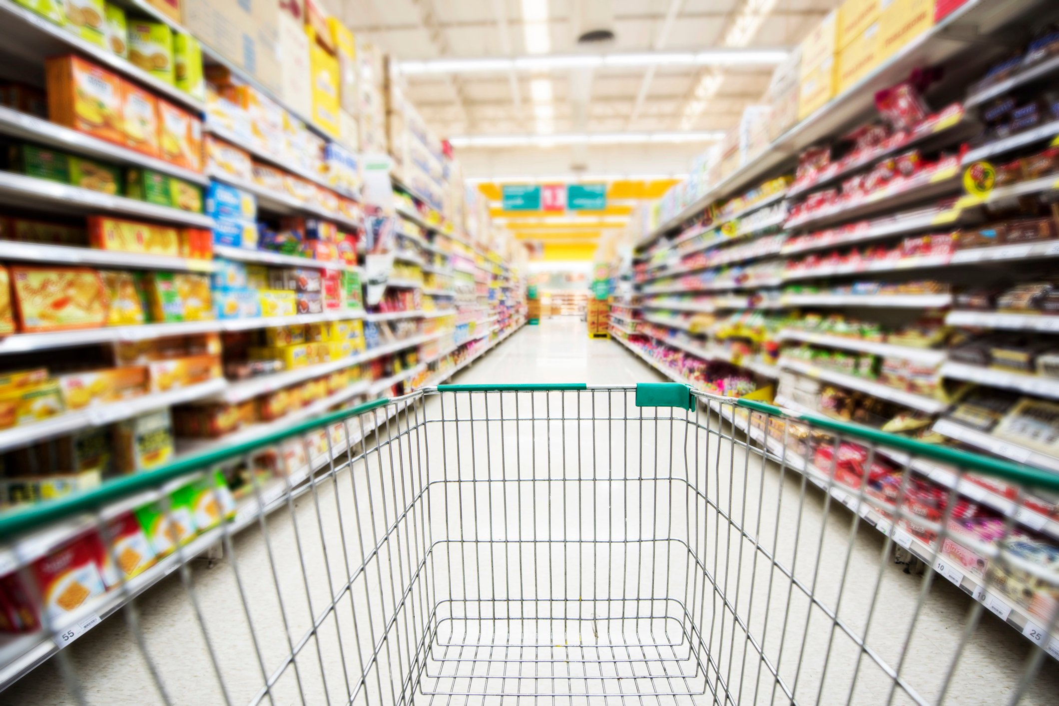 A shopping cart in a store aisle. 
