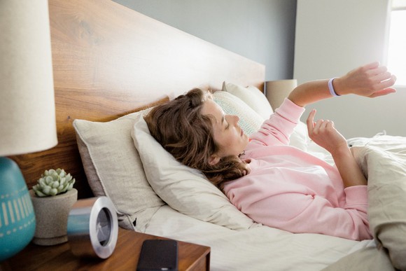 A woman checking her Fitbit Flex 2 in bed.
