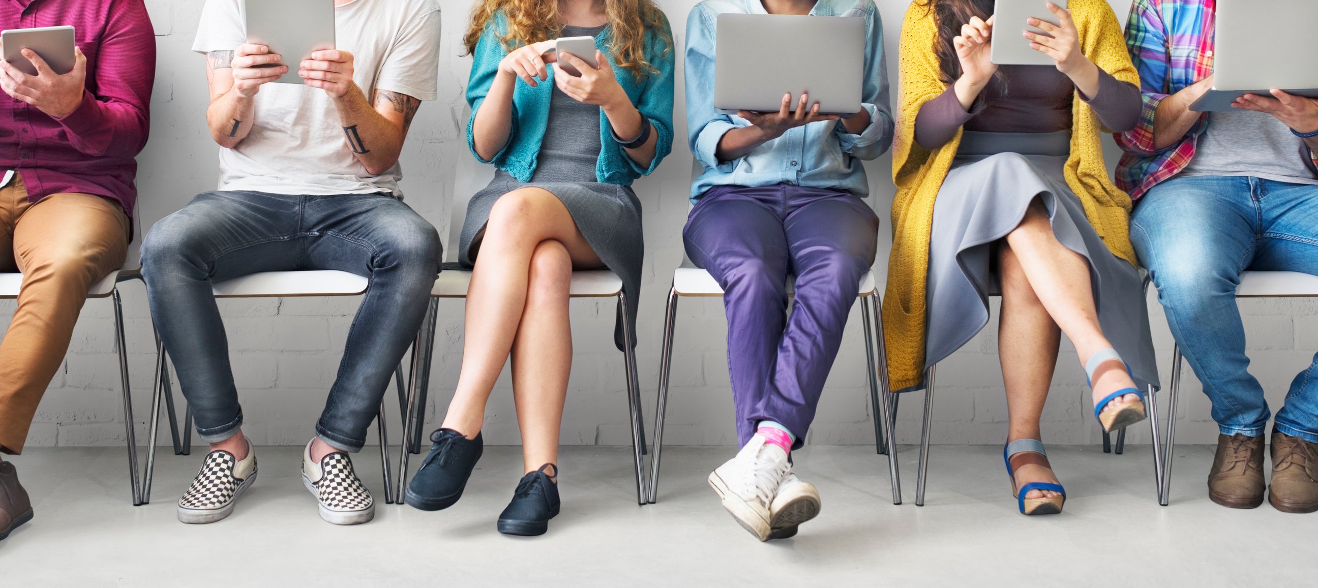 Seated people looking at laptops, tablets, and smartphones