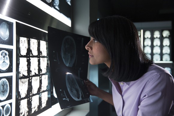 Woman viewing lighted panel of X-ray images