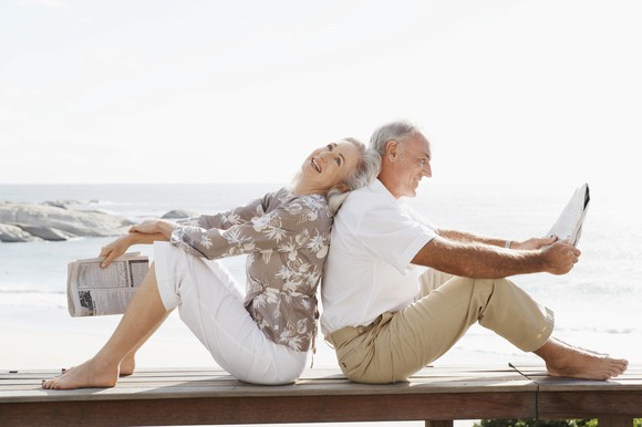 An elderly man and woman sitting back to back. 