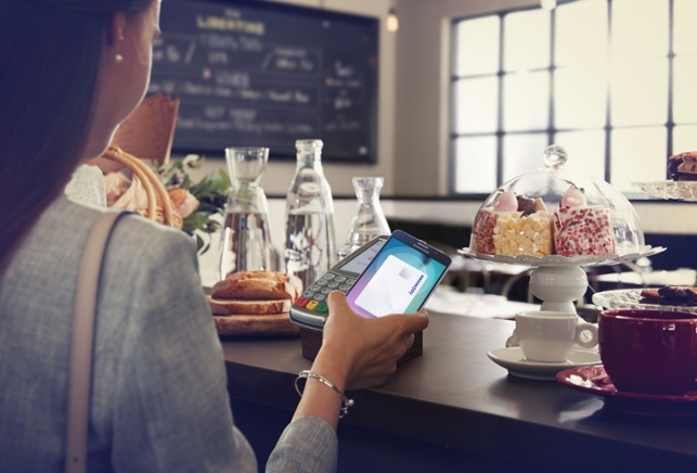 Lady using her Samsung smartphone to pay at a shop to complete a transaction using Samsung Pay