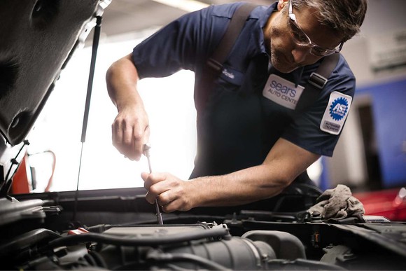 Mechanic working on vehicle at a Sears Auto Center.