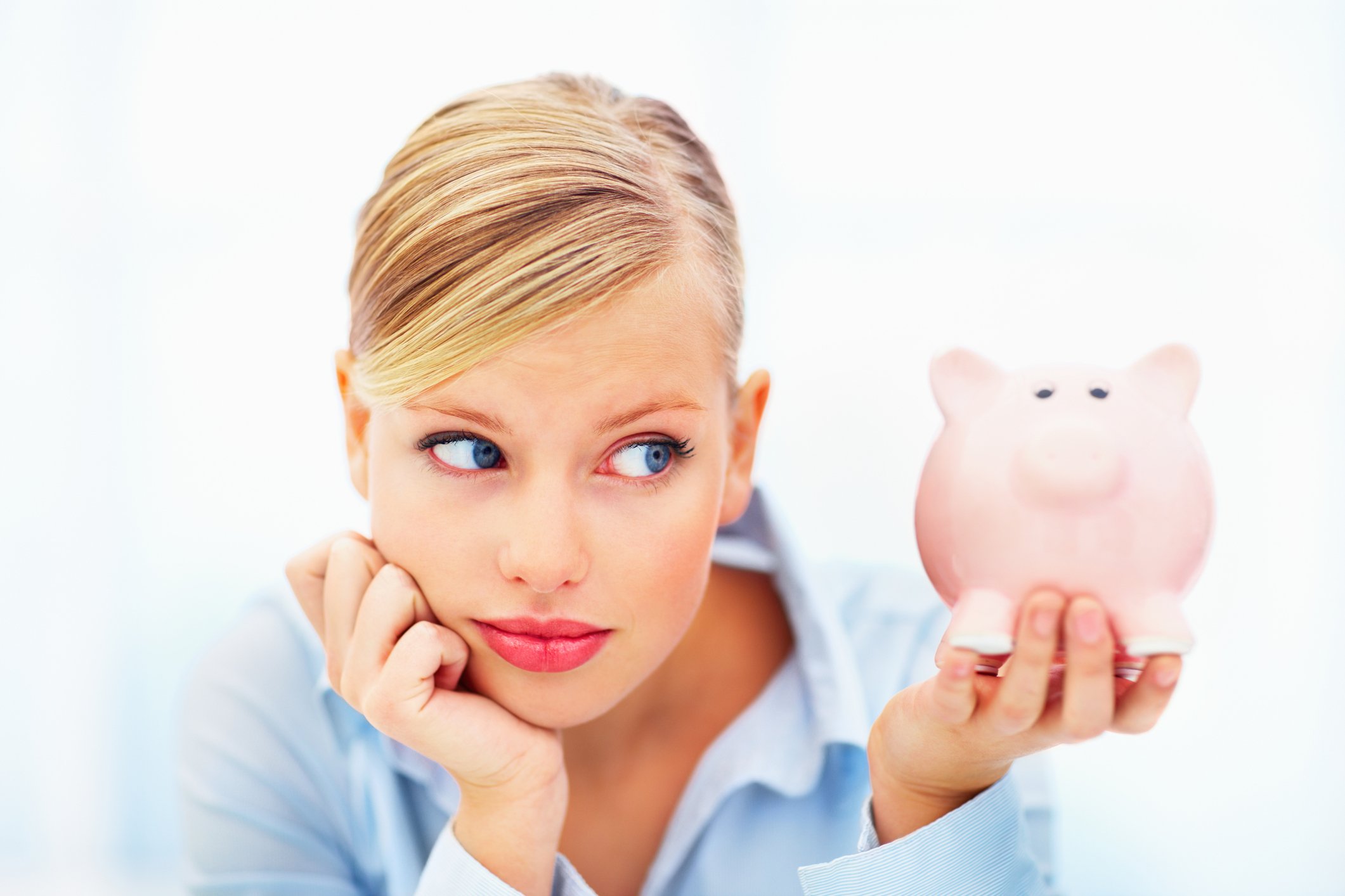 A young woman uncomfortably staring at her piggy bank.