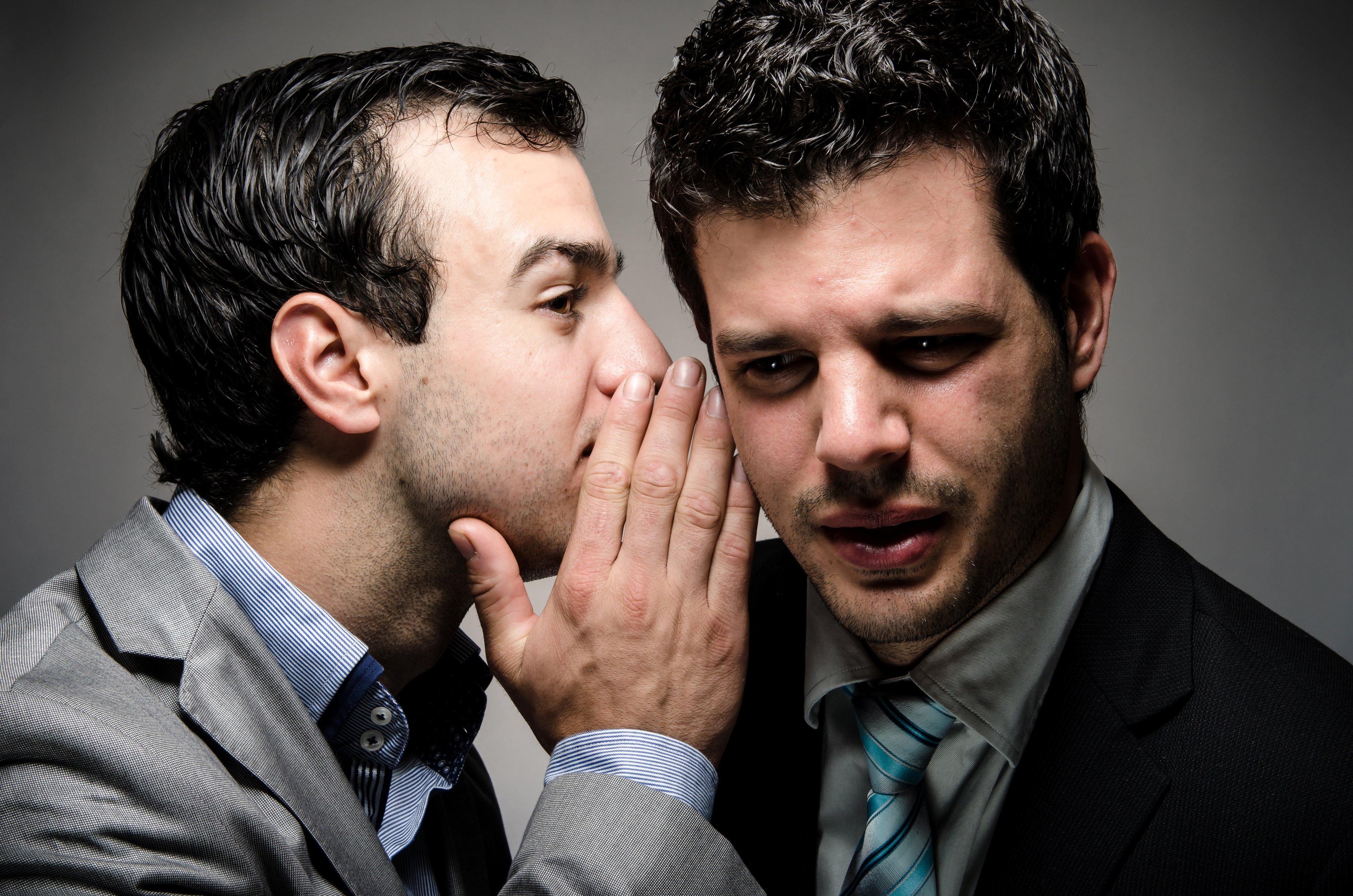 Businessman whispering in the ear of another businessman