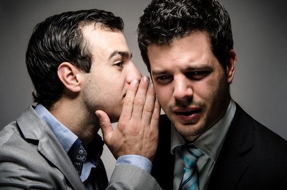 Businessman whispering in the ear of another businessman