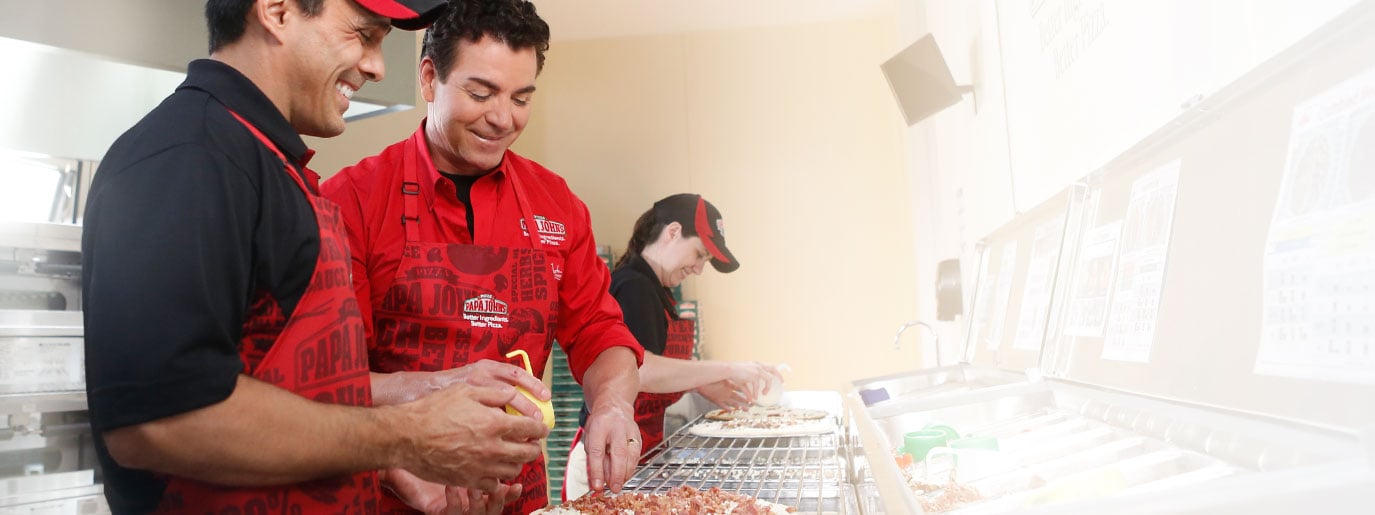 Papa John's founder John Schnatter works in the kitchen with an employee.