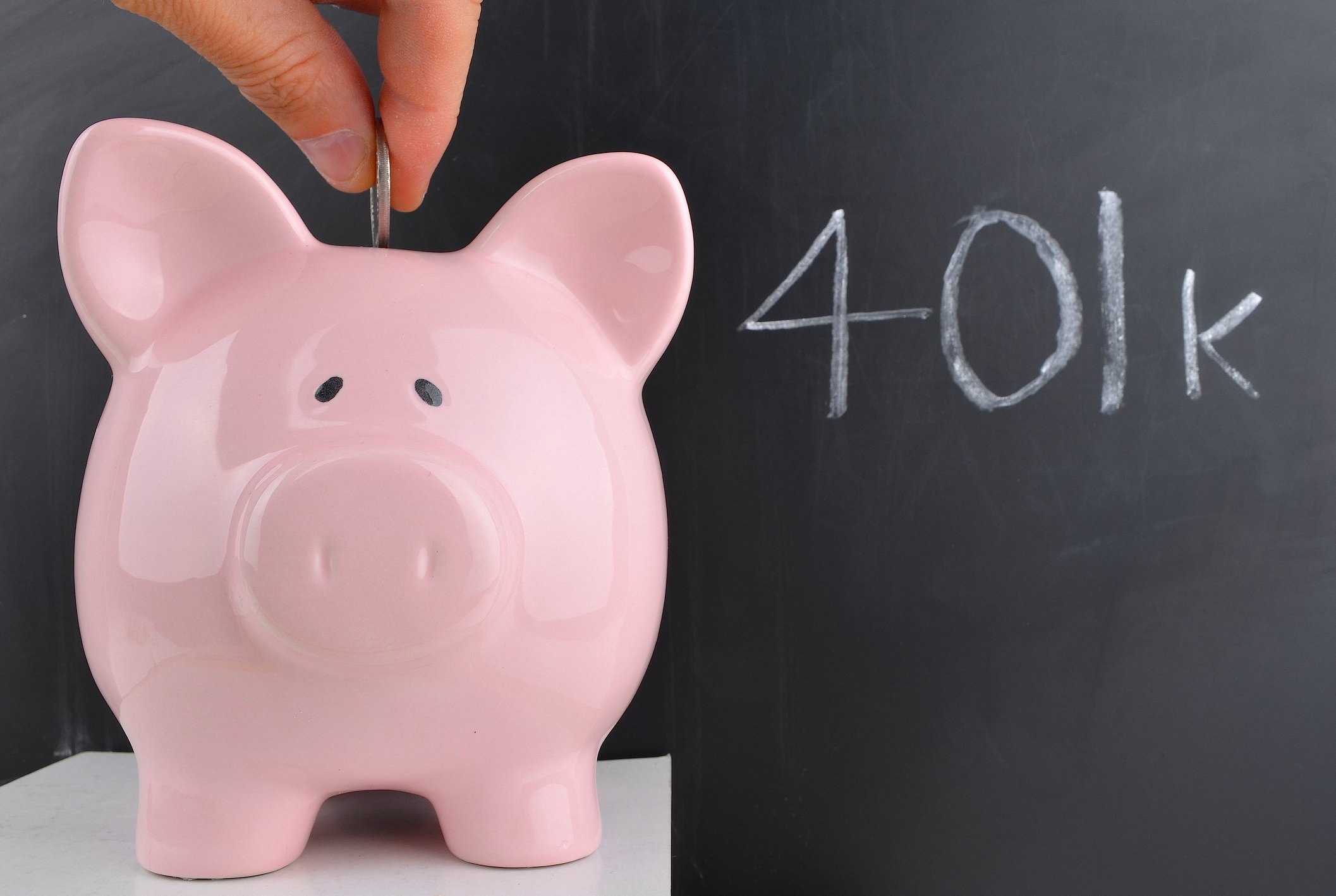Piggybank in front of chalkboard with 401(k) written on it.