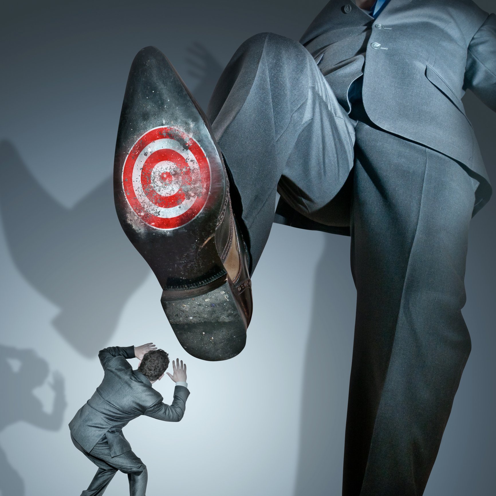 A giant businessman about to stomp on a smaller businessman -- with a target on the bottom of his shoe.
