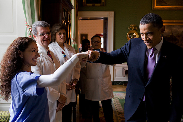 Former President Barack Obama bumping fists with a nurse in the White House and celebrating the passage of the Affordable Care Act.