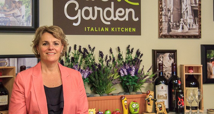 A woman standing behind the counter at Olive Garden.