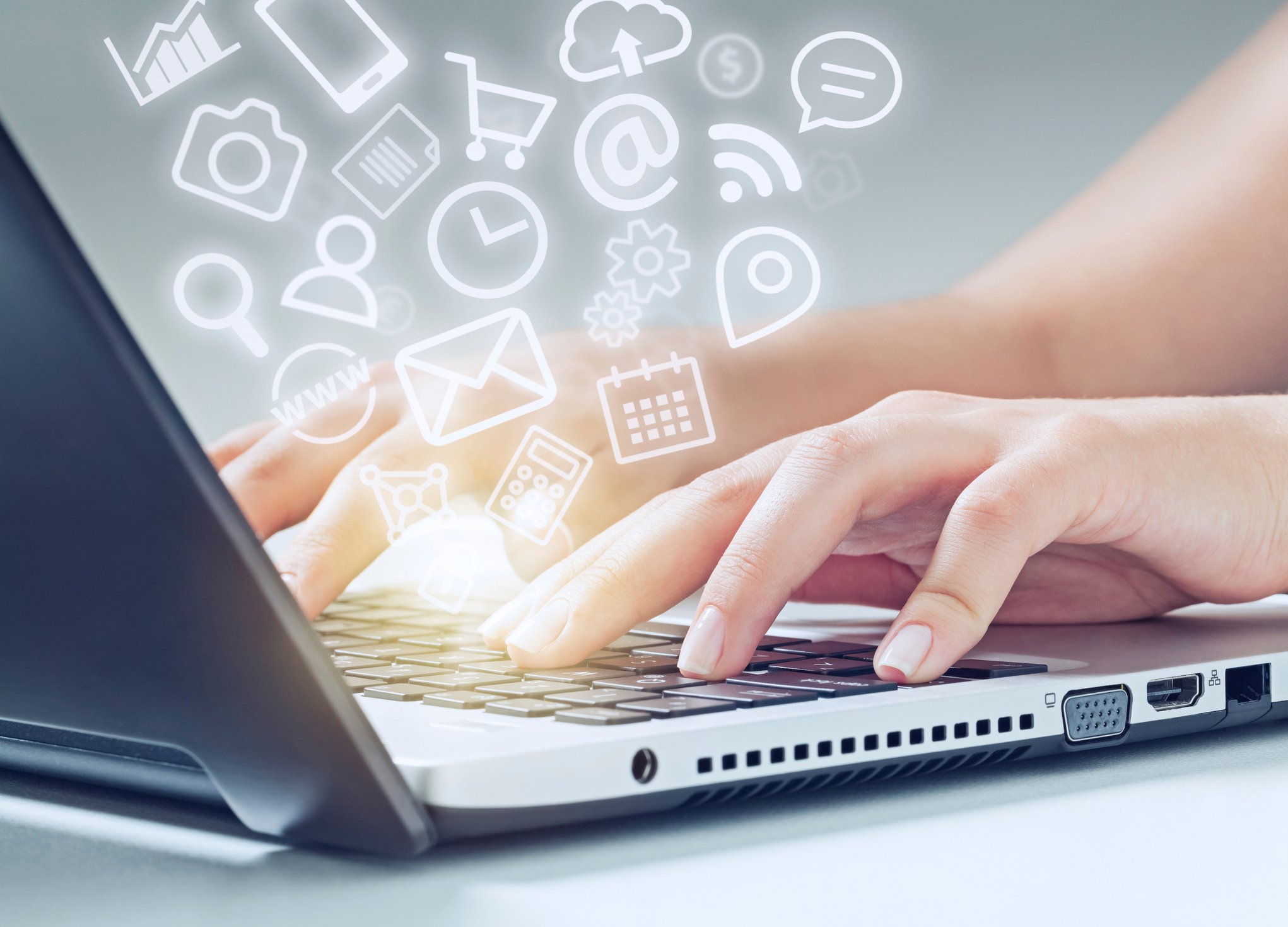 A woman types on a laptop keyboard, and a cloud of icons "floats" out.